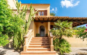 A building with a staircase leading to an entrance, surrounded by cacti and palm trees. - 3 bedroom cozy home in SEstanyol (SEstanyol)