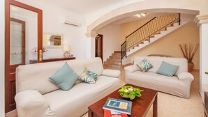 Una sala de estar con dos sofás, una mesa de centro con libros y una escalera.