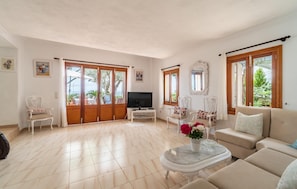 A spacious living room with a large TV, comfortable seating, and a view of the outdoors. - Awesome home in Alcudia with WiFi (Alcudia)