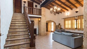 Ein geräumiger Wohnbereich mit Treppe, einer Kandelaber und einem Sofa.