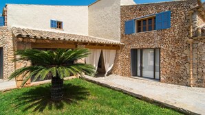 Un edificio de piedra con techo de tejas, una palmera y un patio cubierto de césped.
