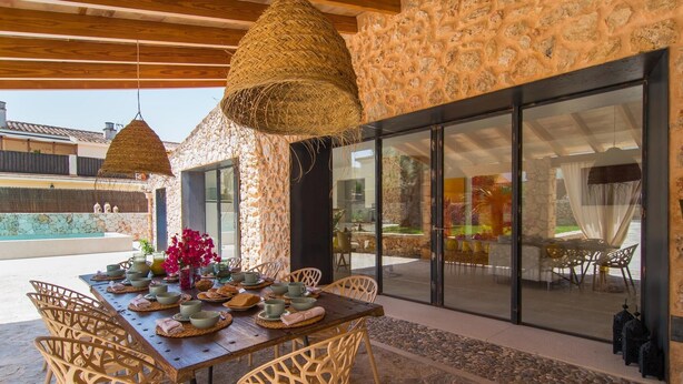 Un comedor con pared de piedra, un ventanal y vista al interior.