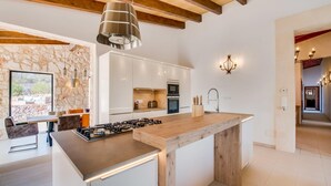 A modern kitchen with a central island, built-in oven, and a stone wall.