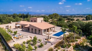 A villa with a swimming pool, outdoor seating, and a view of the surrounding landscape.