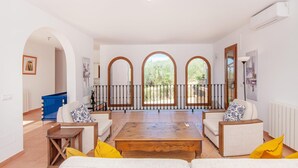 A spacious living room with a wooden coffee table, two sofas with patterned cushions, and a balcony with a metal railing. - Beautiful home in Felanitx with sauna (Felanitx)