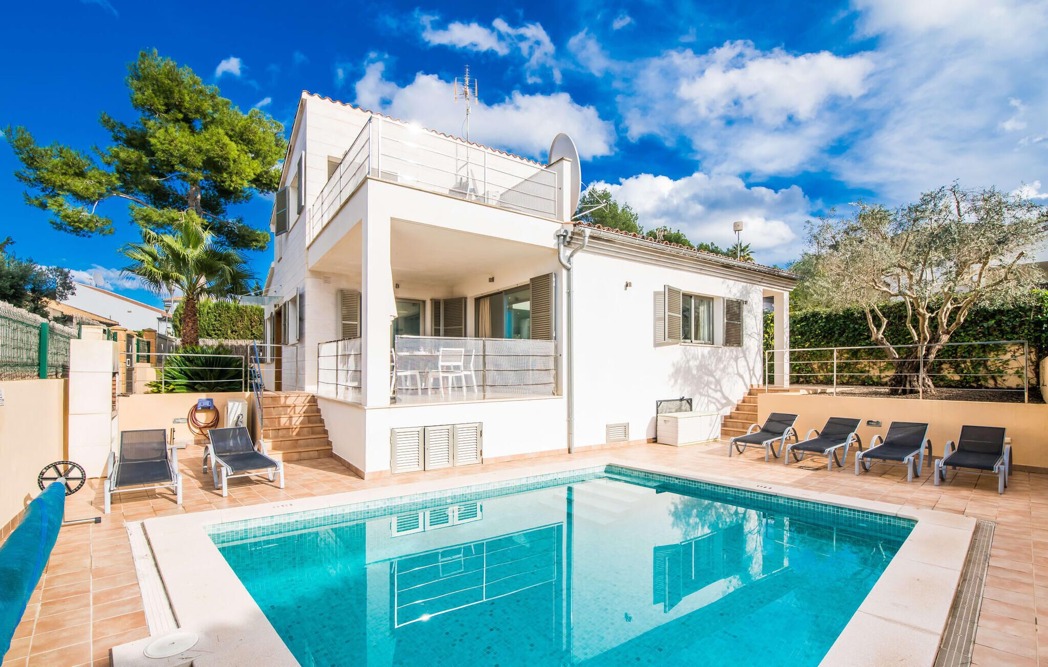Una casa a due piani con piscina, area relax all'aperto e un balcone.