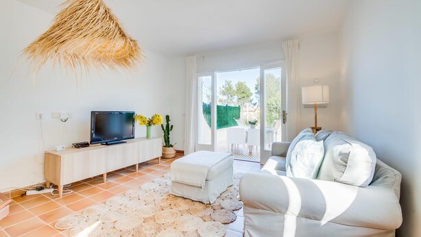 A modern living room with a flat-screen TV, a white sofa, a small table, and a hanging light fixture. - Awesome home in Son Serra de Marina with WiFi (Son Serra de Marina)