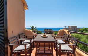 Varanda com mesa e quatro cadeiras, com vista para a costa.
