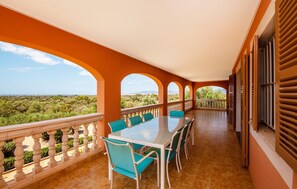 A balcony with a table and chairs, offering a view of a landscape with trees and distant mountains. - Cozy home in Santa Maria with sauna (Santa Maria)