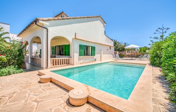 Eine Villa mit Swimmingpool, Sitzgelegenheiten im Freien und einem Garten.