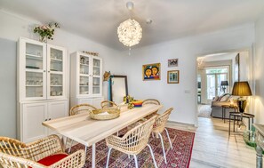 A dining area with a wooden table, wicker chairs, a red and white patterned rug, and white cabinets with glass doors. - Cozy home in Arta with private swimming pool, can be inside or outside (Arta)