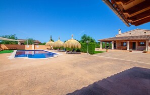 Un área de piscina con jacuzzi, sillas de descanso y una zona de estar cubierta.