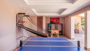 A ping pong table with a net, a foosball table, and a red flower painting in a room with beige walls and a ceiling with recessed lighting. - Lovely home in Binissalem with private swimming pool, can be inside or outside (Binissalem)