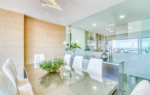A modern dining area with a glass table, white chairs, and a potted plant. - Luxurious home in Son Serra de Marina with WiFi (Son Serra de Marina)