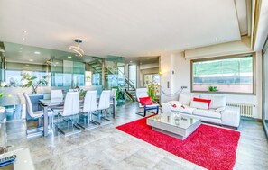 Un salon moderne avec une table basse en verre, des canapés blancs et un tapis rouge.