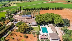 Luchtbeeld van een pand met een zwembad, zonnepanelen en een grote tuin.