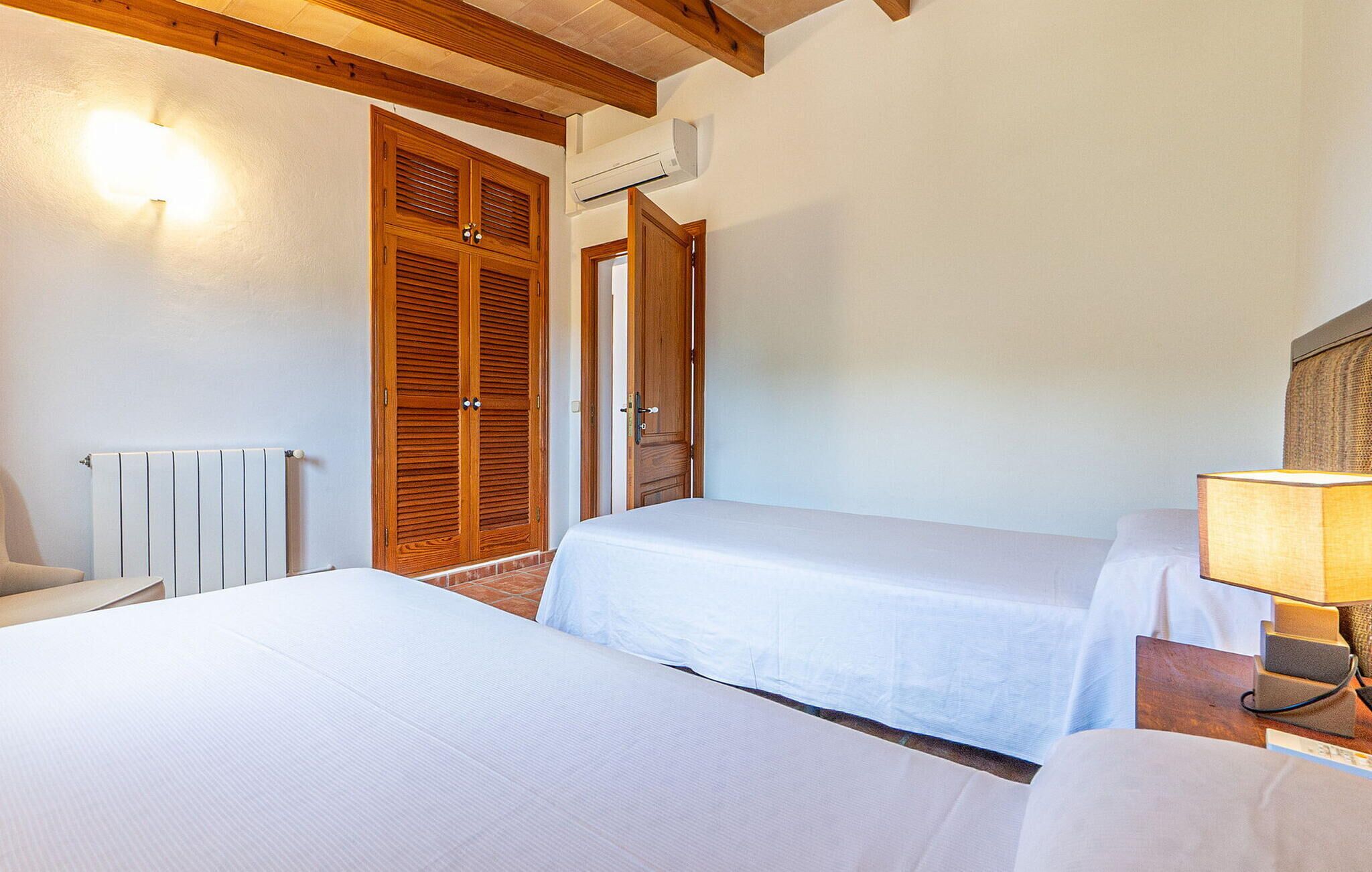 A hotel room with two beds, a radiator, wooden doors, and a lamp.