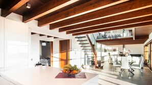 Una cucina moderna con isola centrale, travi in legno e una scala che conduce a un piano superiore.