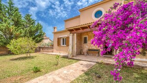Una casa con un vialetto in pietra che conduce a una panchina di legno e un muro in pietra.