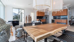A spacious living area with a large wooden dining table, modern kitchen, and a view of the outdoors. - Awesome home in Porto Cristo (Porto Cristo)