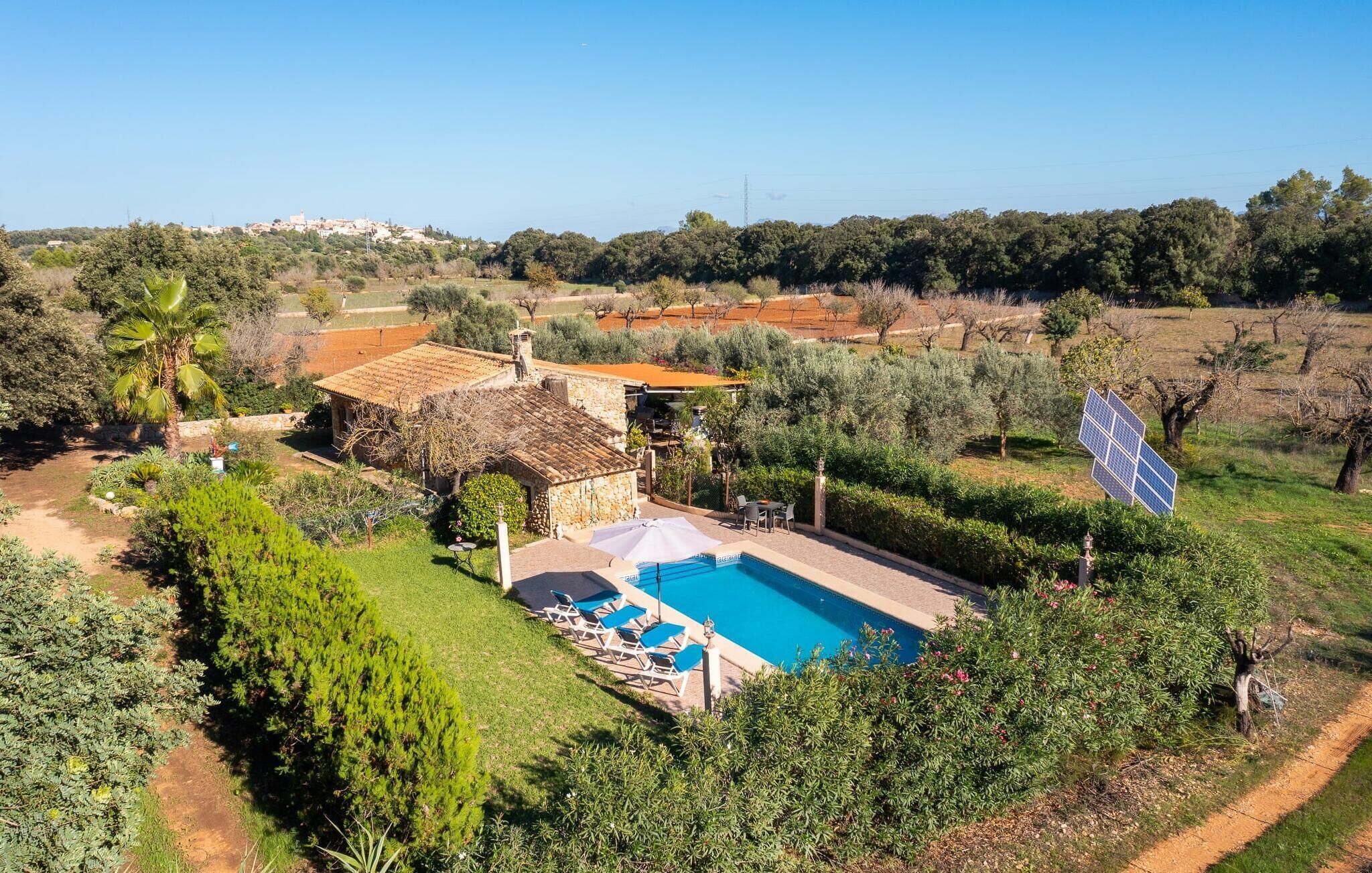 Eine Villa mit Swimmingpool, Sitzgelegenheiten im Freien und Solaranlage.
