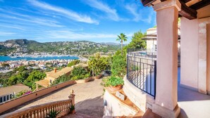 A balcony with a view of a coastal town, a pool, and a mountain backdrop. - Lovely home in Port d'Andratx with sauna (Port d'Andratx)