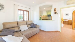 A living room with a beige sofa, a kitchen area with a green countertop, and a dining area with a wooden table and chairs. - Stunning home in Son Serra de Marina with house sea view (Son Serra de Marina)