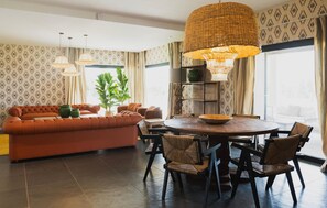 A modern living room with a sofa, dining table, chairs, and a large hanging light fixture. - Flor de Sal a Sa Canoveta (Campos)