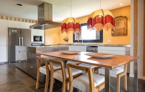 A modern kitchen with a central island, stainless steel appliances, and a decorative hanging light fixture. - Flor de Sal a Sa Canoveta (Campos)