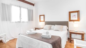 A hotel room with a bed, two bedside tables, a chair, and a window with sheer curtains. - 3 bedroom gorgeous home in Alcudia (Alcudia)