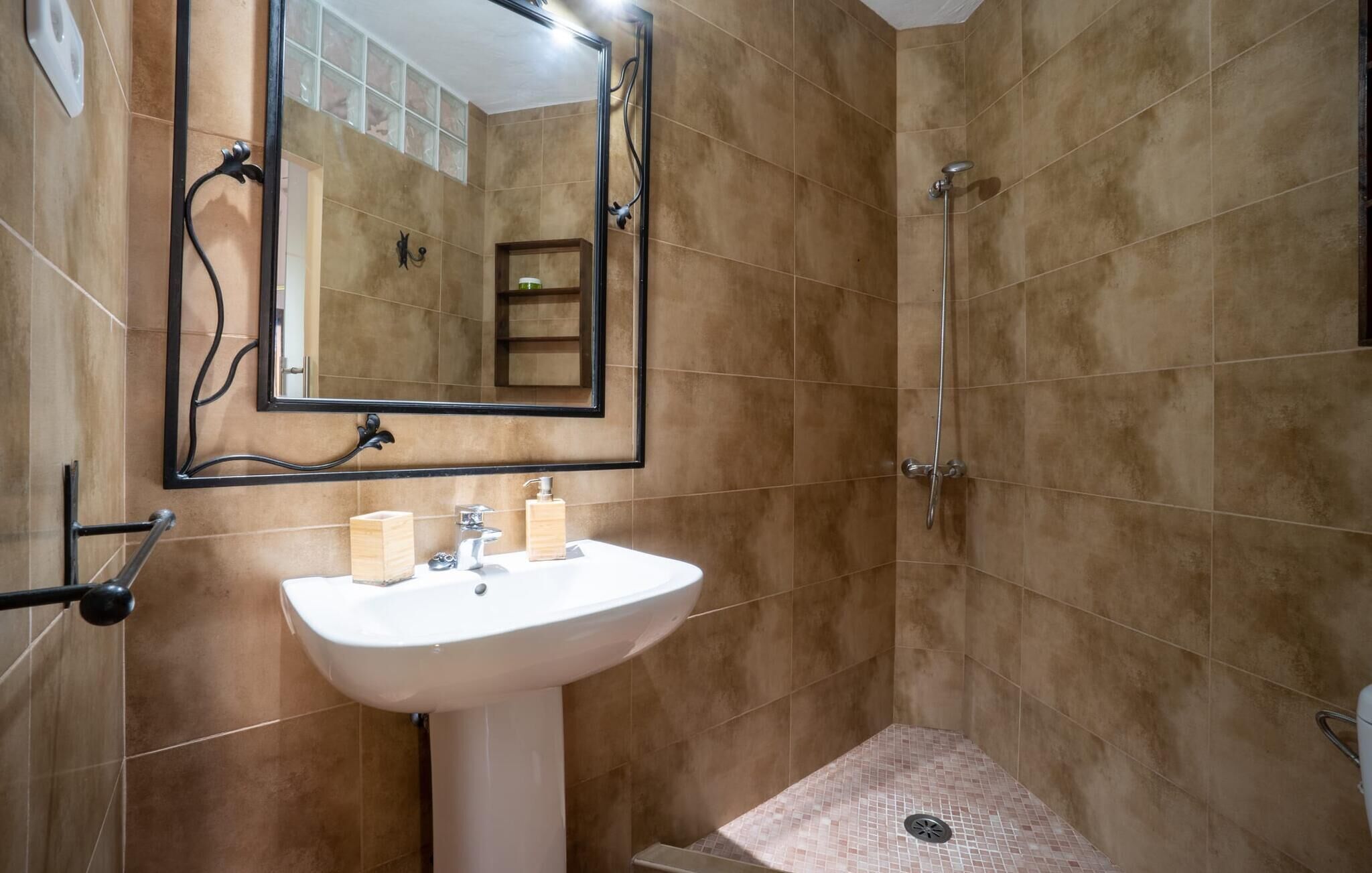 A bathroom with a white sink, mirror, and shower.