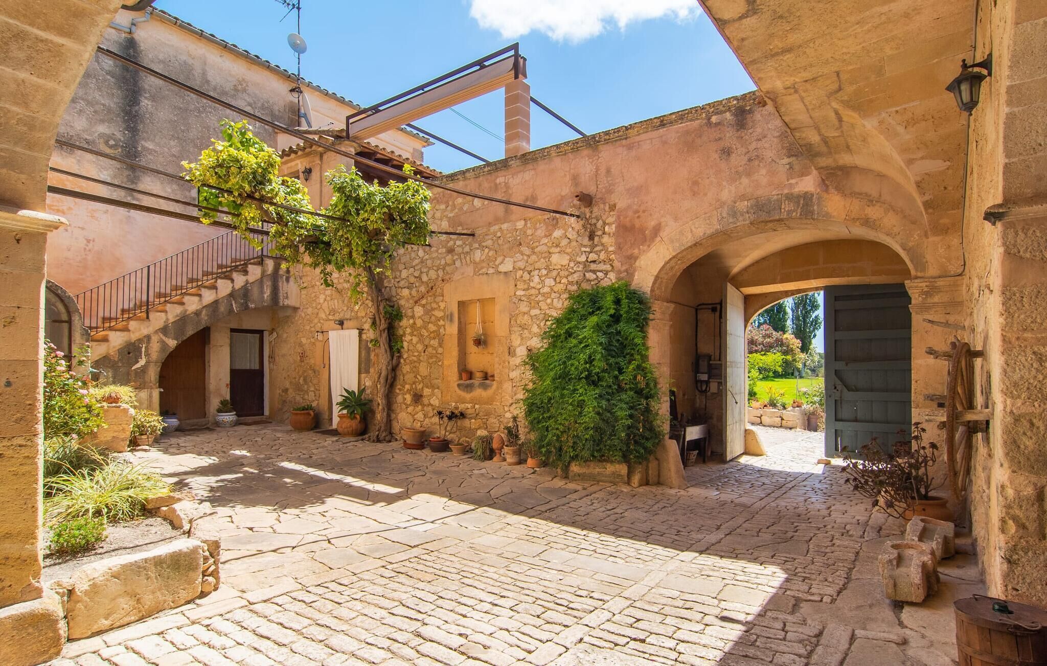 A courtyard with stone walls, a wooden door, and potted plants.