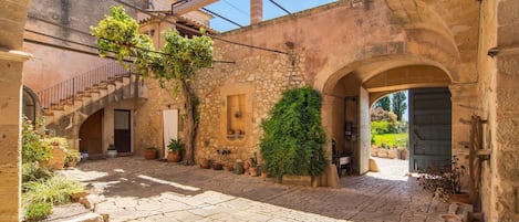 A courtyard with stone walls, a wooden door, and potted plants.