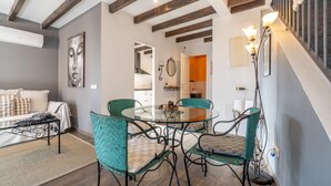 Uma sala de estar moderna com uma mesa de jantar de vidro cercada por quatro cadeiras, um sofá e um grande quadro abstrato.