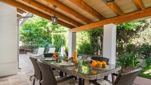 Eine Terrassengruppe mit Glastisch, Korbstühlen und einer hängenden Laterne.