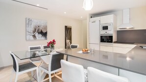 Eine moderne Küche mit weißen Schränken, einem eingebauten Backofen und einer großen Kochinsel mit Sitzgelegenheiten.
