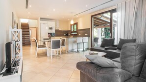 Ein modernes Wohnzimmer mit grauem Sofa, Couchtisch und Essbereich, im Hintergrund eine Küche.