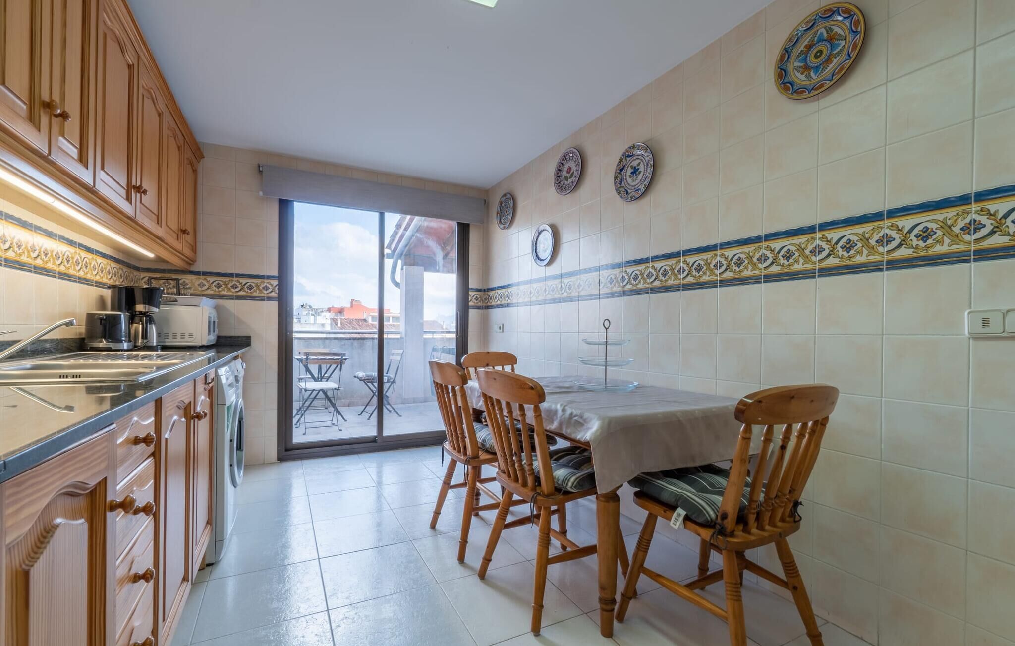 A kitchen with wooden cabinets, a dining table with four chairs, and decorative plates on the wall.