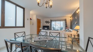 Un espace repas moderne avec une table en verre, des chaises en métal et un lustre.