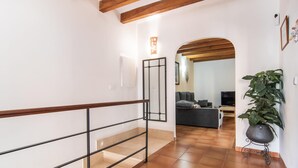 A staircase with a wooden handrail leading to a living area with a sofa, a television, and a large potted plant. - 3 bedroom gorgeous apartment in Soller (Soller)