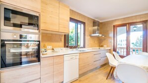 Una cuina moderna amb armaris de fusta, forn integrat i rentaplats.