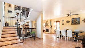 A spacious living area with a staircase, a fireplace, and a dining area with chairs and a table. - Beautiful home in Pollenca with private swimming pool, can be inside or outside (Pollenca)