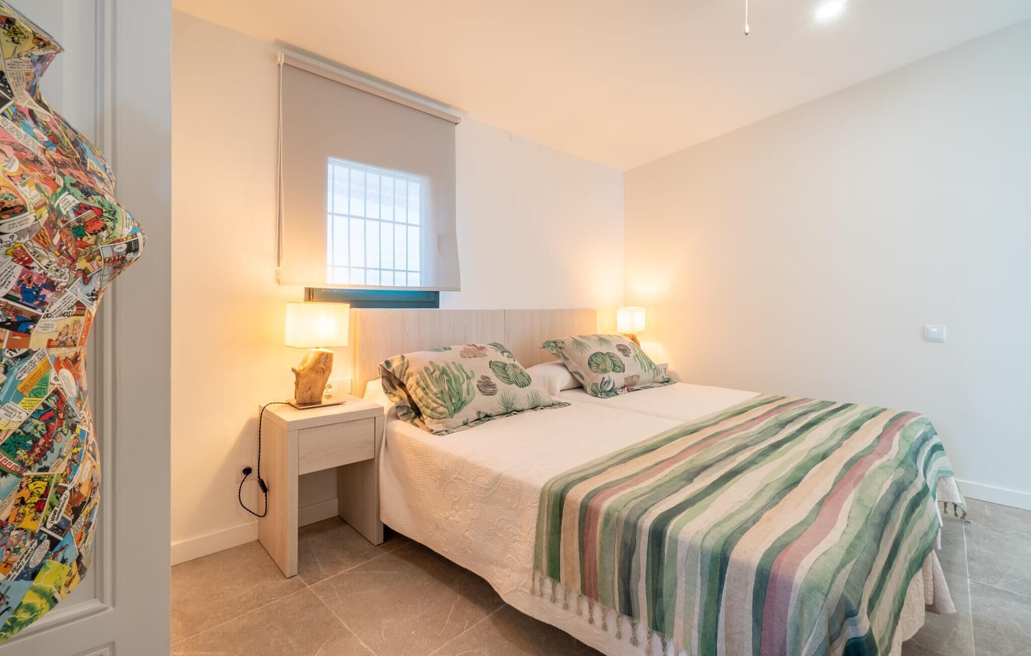 Een slaapkamer met een bed, nachtkastjes, een spiegel en een raam.