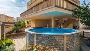A swimming pool with a stone wall, a wooden staircase, and a balcony. - Amazing home in Porto Cristo (Porto Cristo)