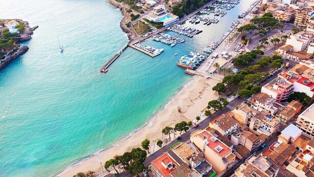 An aerial view of a coastal town with a marina, beach, and dense urban buildings. - Amazing home in Porto Cristo (Porto Cristo)