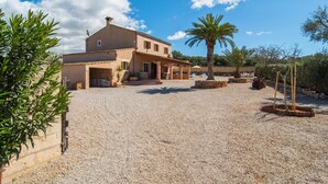 Una casa de dos pisos con camino de grava, un porche cubierto y una palmera.