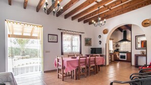 Comedor con una mesa dispuesta para seis personas, sillas de madera y una araña.