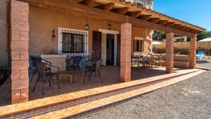Un patio techado con mobiliario exterior y una pared de piedra.