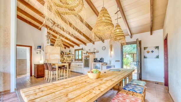 A spacious kitchen with a long wooden table, a dining area with chairs, and a hanging light fixture. - Luxurious home in Campos with private swimming pool, can be inside or outside (Campos)