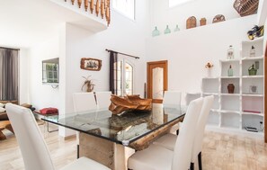 A spacious dining area with a glass table and white chairs, a wooden staircase, and a white shelving unit with decorative items. - Cozy home in Palma with private swimming pool, can be inside or outside (Palma)